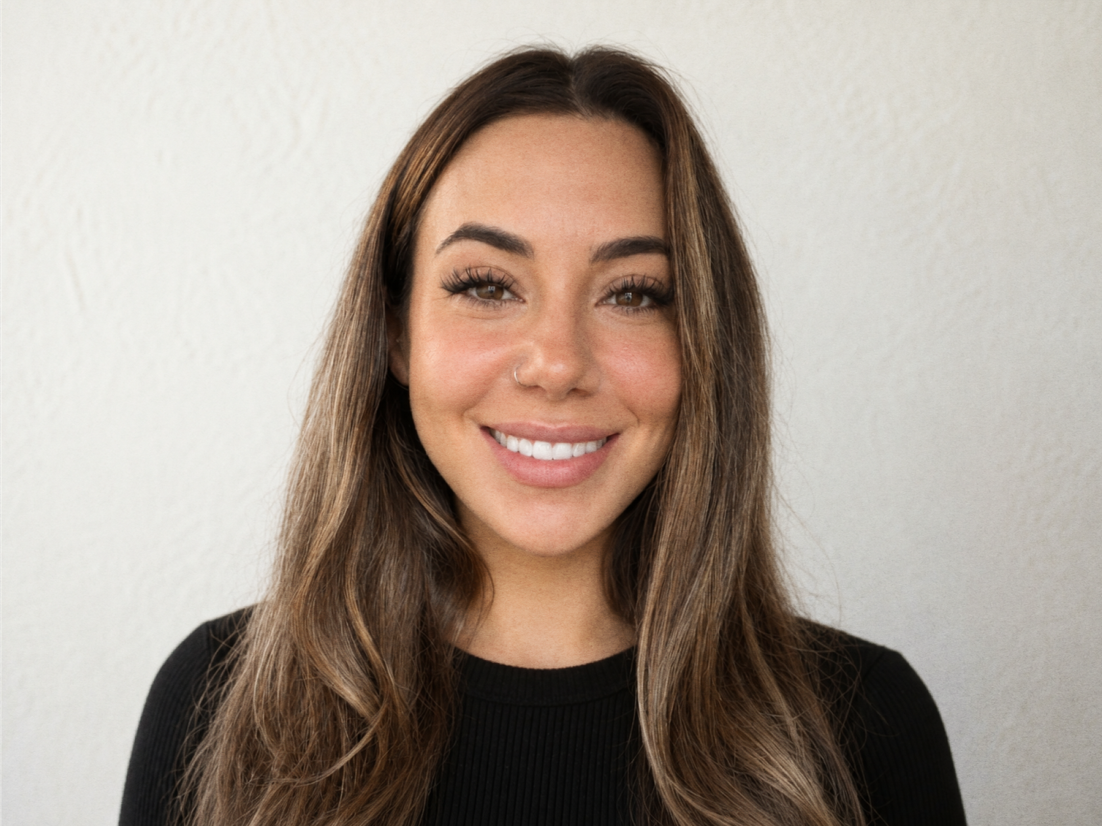 A headshot of Monterey Thompson. A smiling woman with long, brown hair and a nose ring, wearing a black top, against a plain white background.