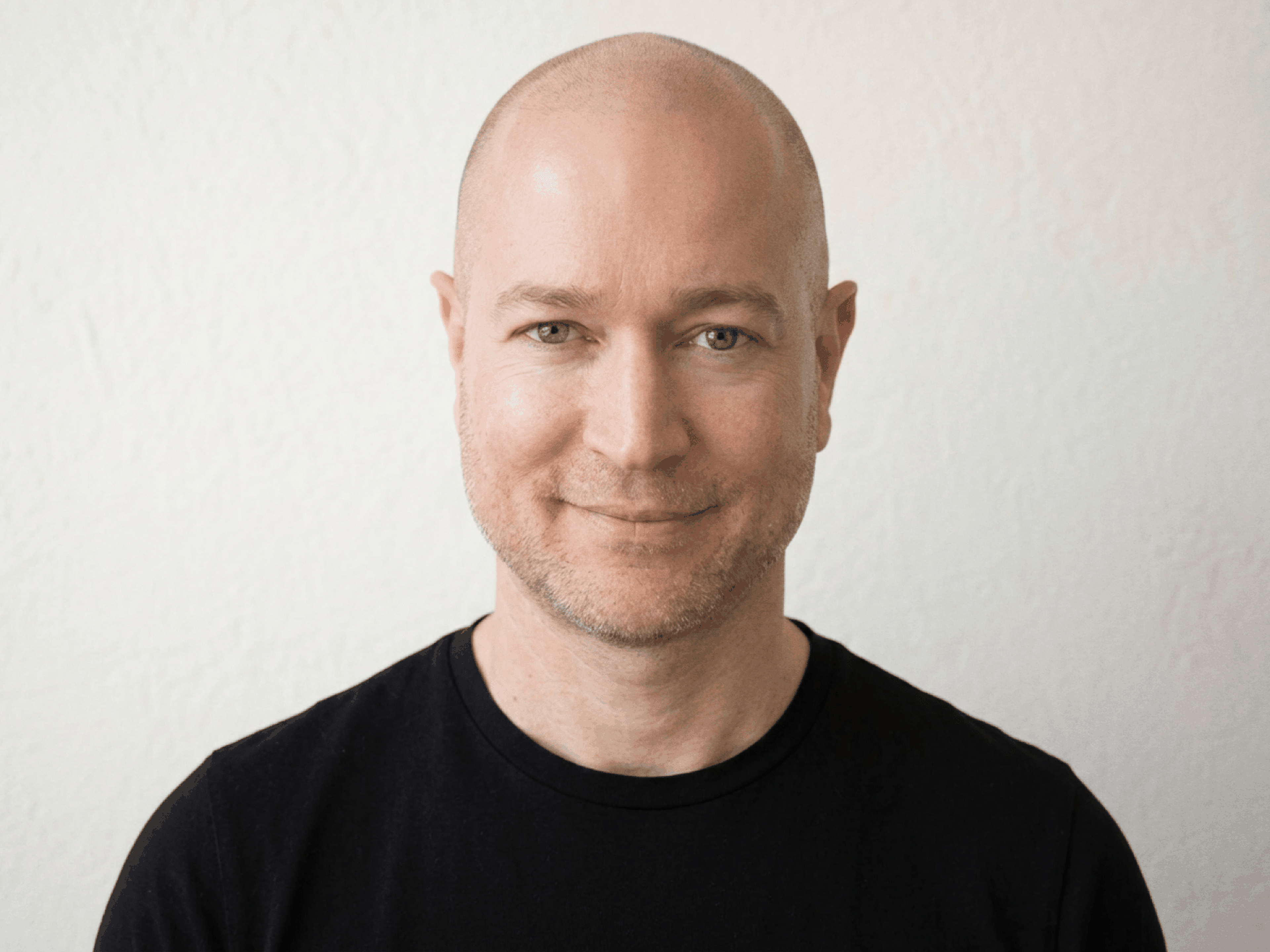 A headshot of David Moradi. A caucasian male with no hair wearing a dark gray t-shirt.