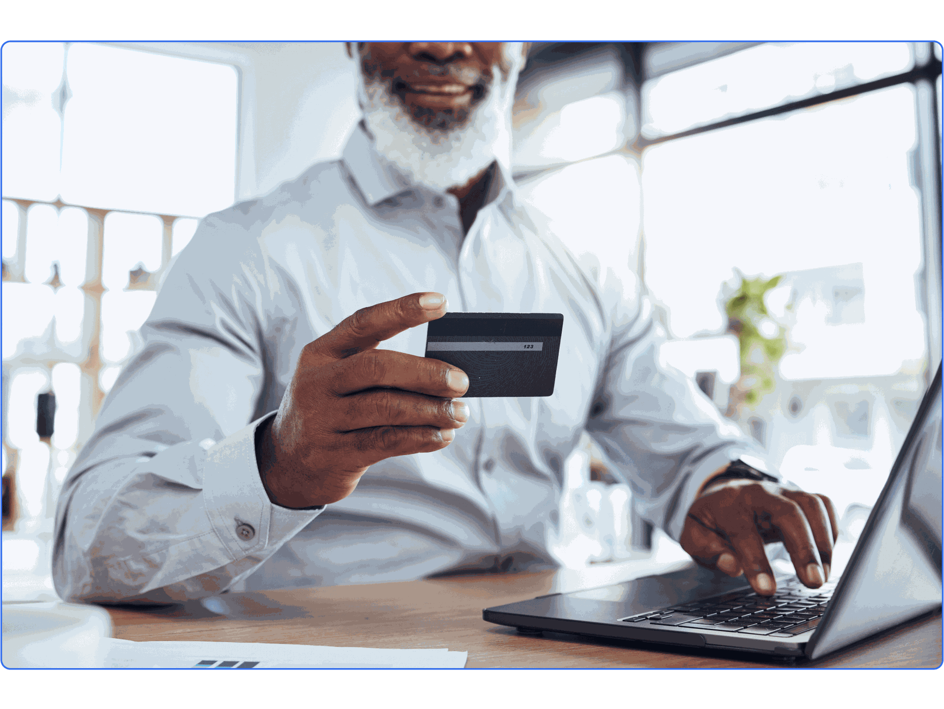 Older black man holding signing into his bank on his computer.