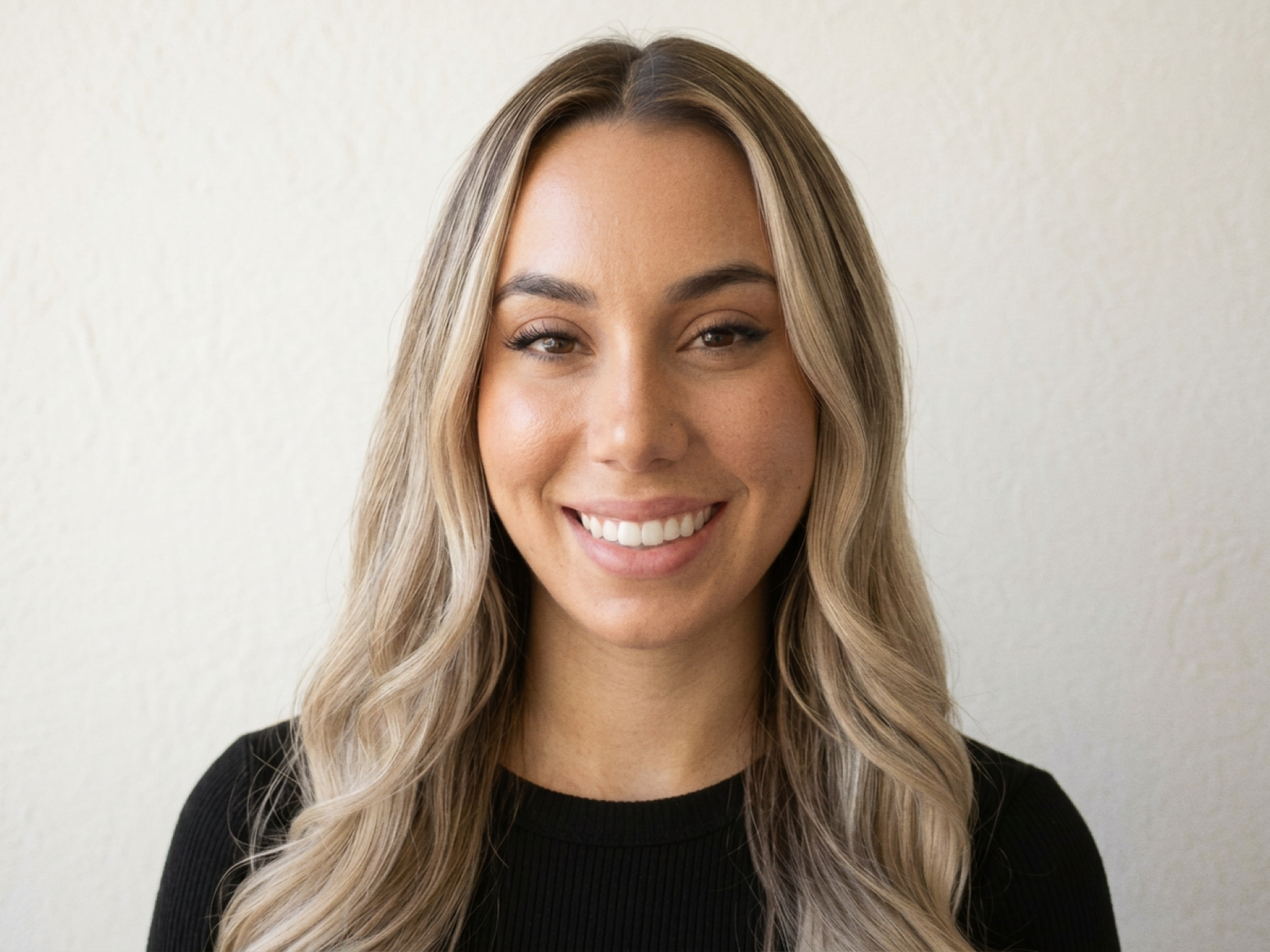 A headshot of Monterey Thompson. A woman with long wavy hair, wearing a black shirt.