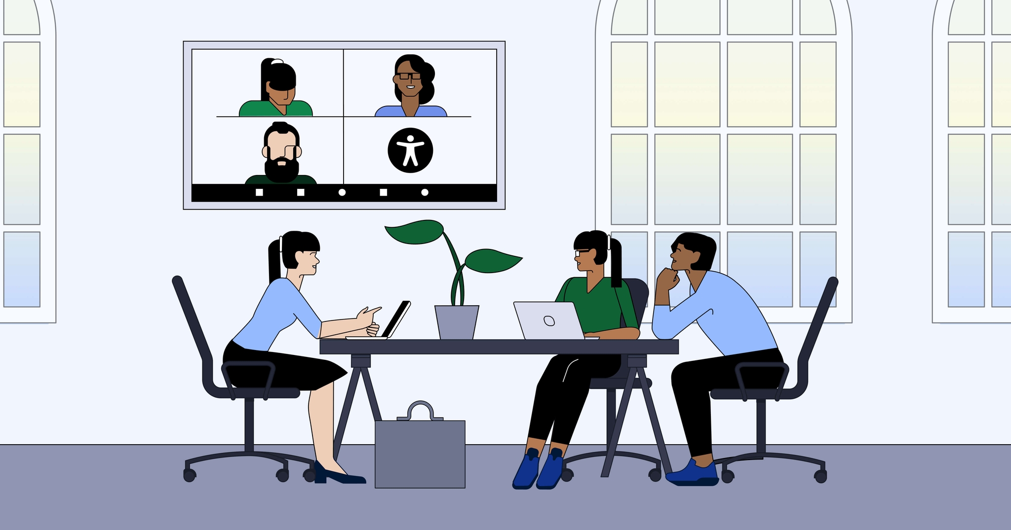Three people at a desk with open laptops, having a video conference with three others displayed on a screen. Two large windows are in the background.