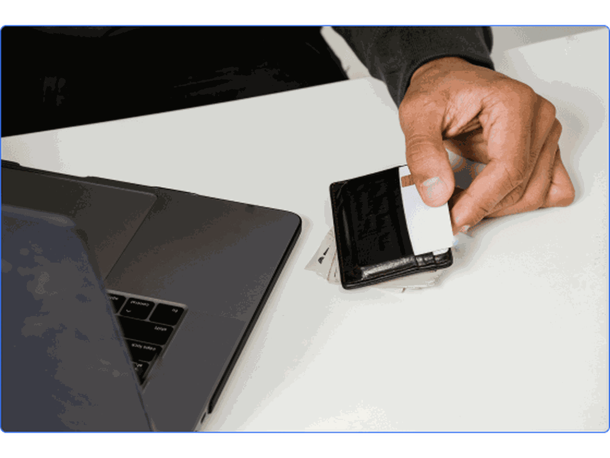 Black man holding a credit card, signing into his bank on his computer.