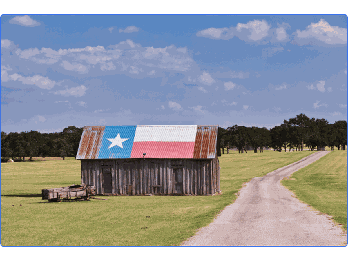Rustic barn with Texas flag painted on roof.
