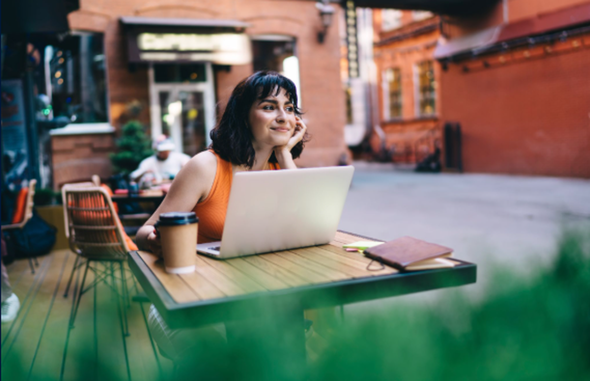 Young woman using a laptop while seated at an outdoor café