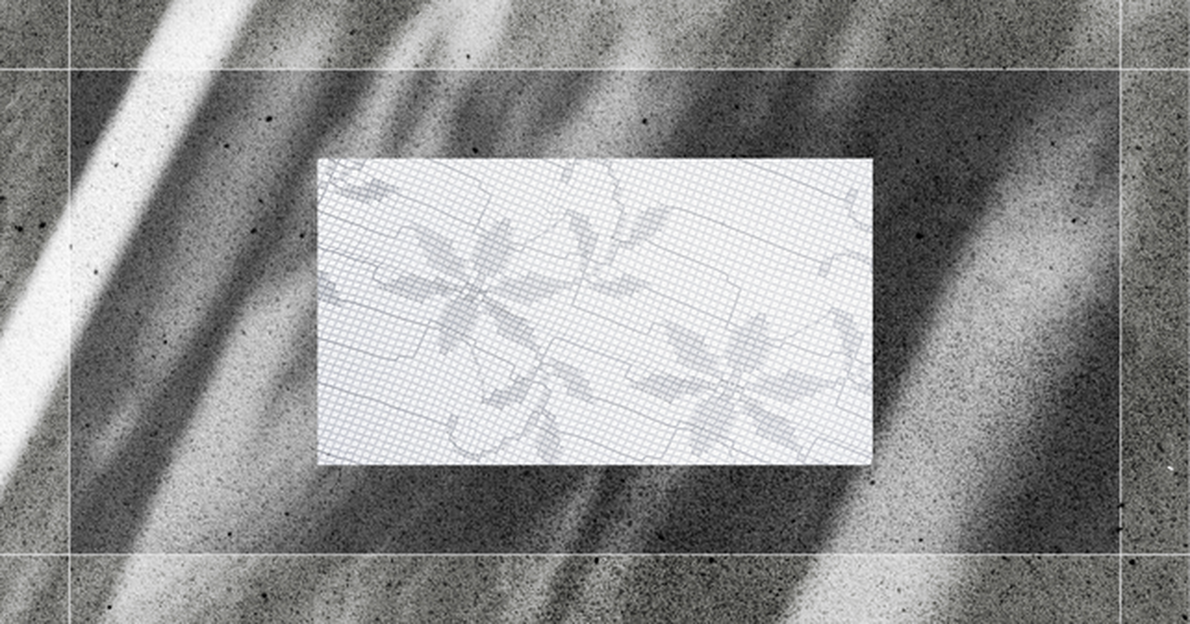 A rectangular piece of graph paper with faint floral designs placed on a textured, shadowed surface.