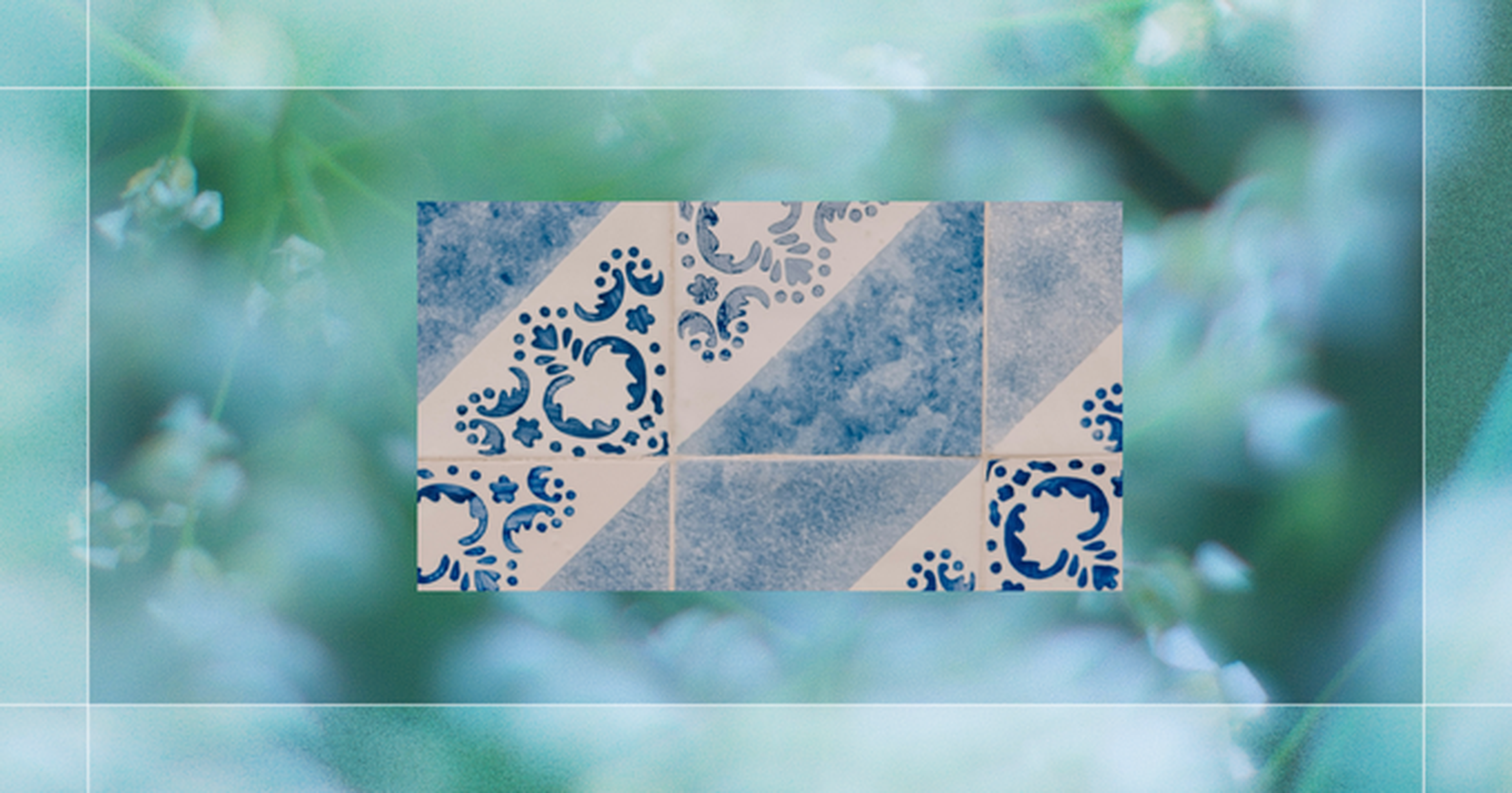 A rectangular design of blue and white tiles with floral and striped patterns is framed by a blurred green and blue background.