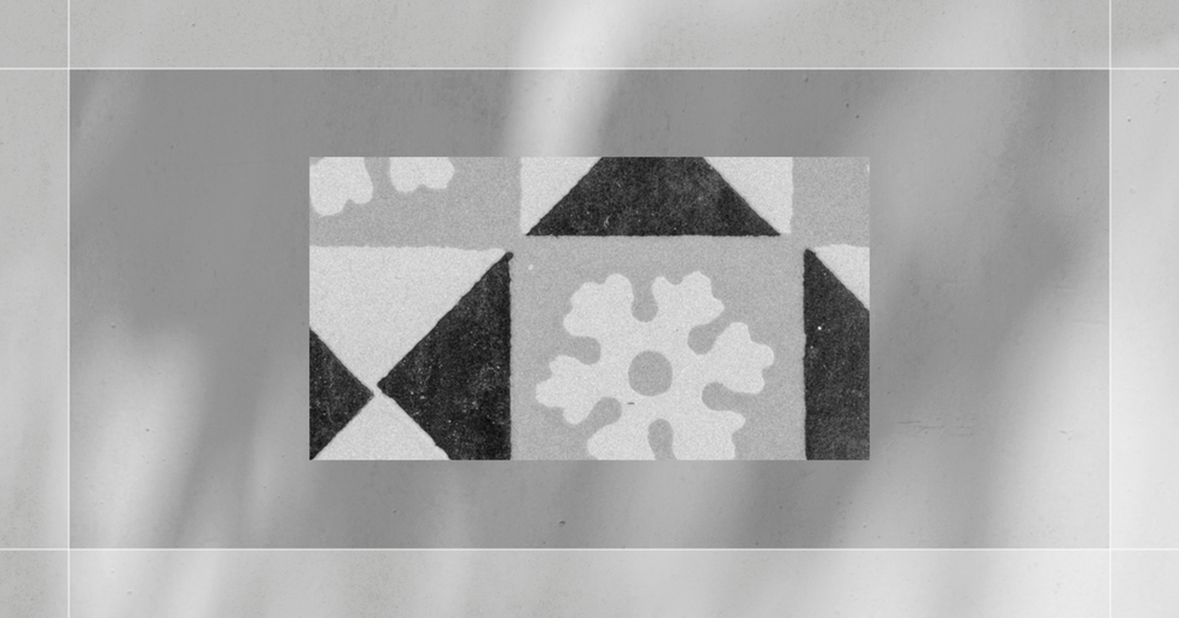 Abstract black and white geometric pattern with triangular shapes and a central floral-like motif, surrounded by a blurred frame.